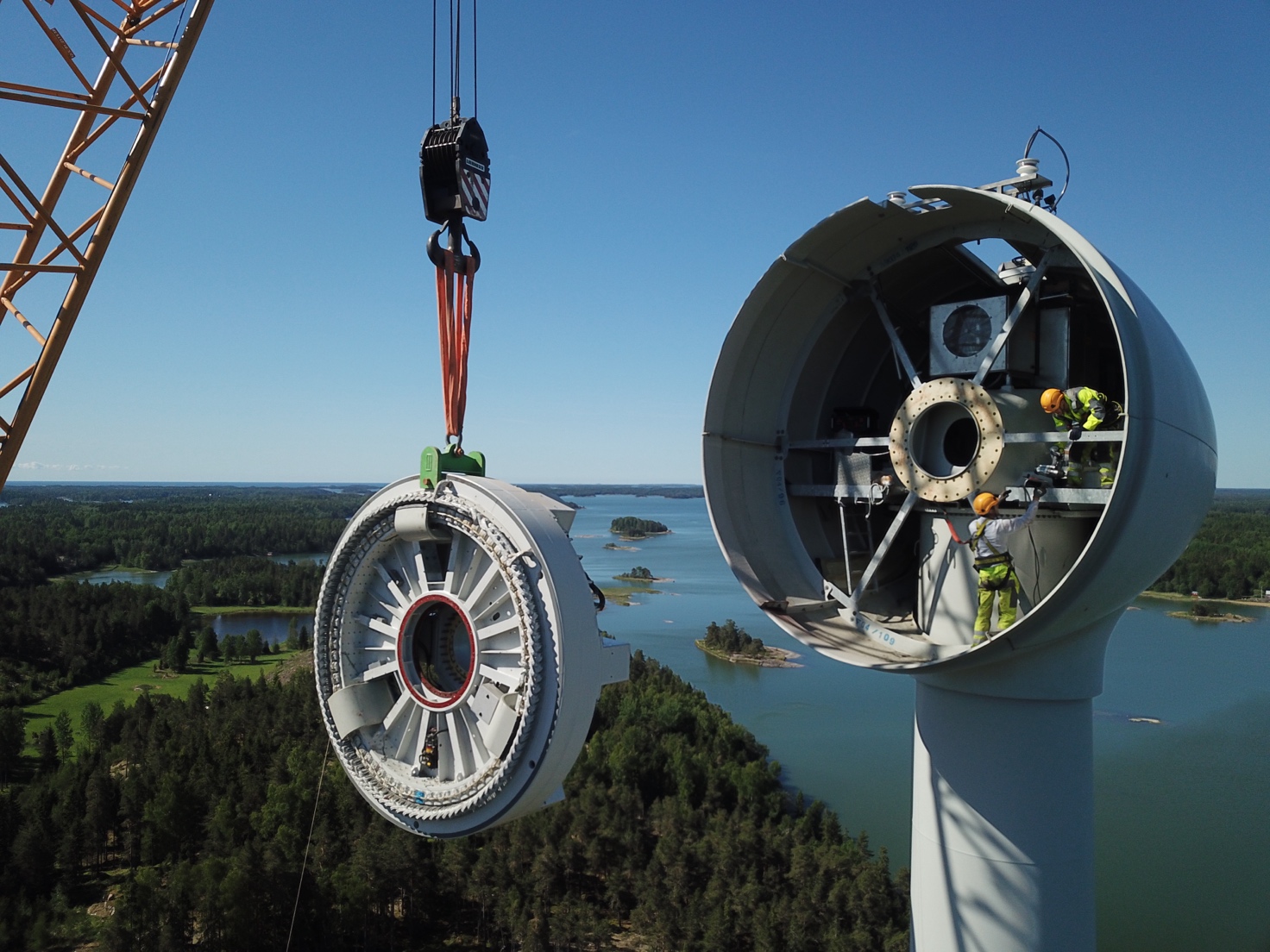 A crane lifting a wind turbine Description automatically generated
